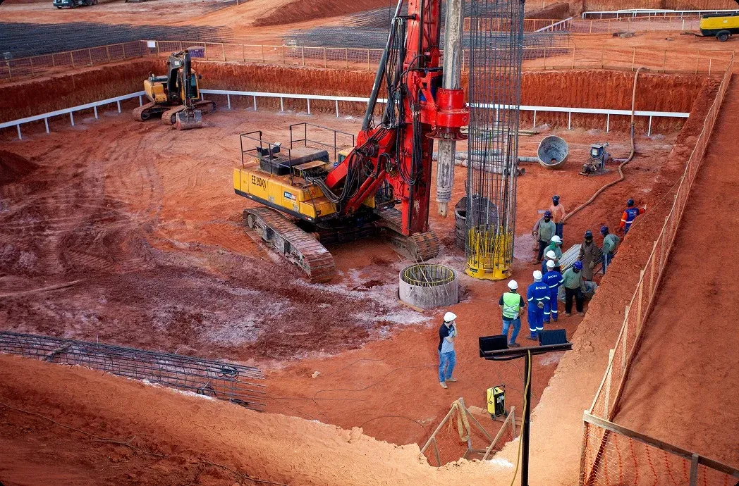 Vista elevada de canteiro de obras com equipamento de perfuração e equipe ao redor de armadura de fundação